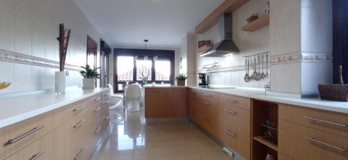 a large kitchen with white counters and wooden cabinets at Itxi y Jamin - Chalet con vistas a la Ria de Vigo in Moaña