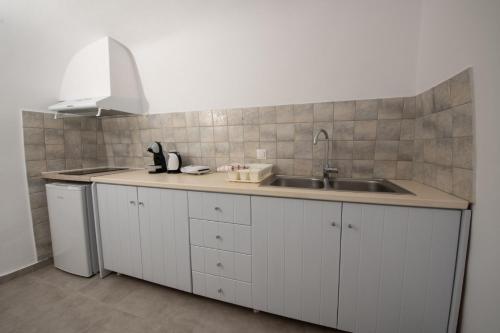 a kitchen with white cabinets and a sink at Sun Angelos Oia - Luxury Cave Suites in Oia