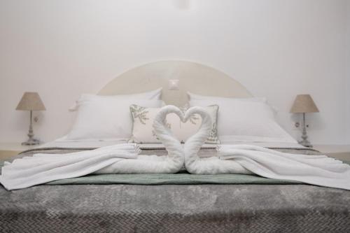 two swans shaped towels on a bed at Sun Angelos Oia - Luxury Cave Suites in Oia