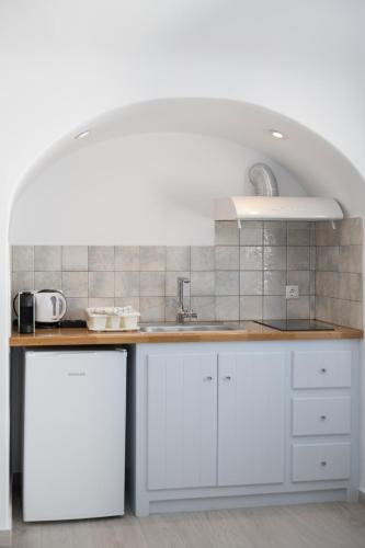 a kitchen with white cabinets and a counter top at Sun Angelos Oia - Luxury Cave Suites in Oia