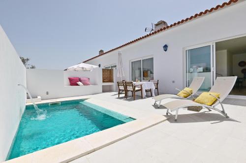 un patio con piscina, sedie e una casa di Sesmarias Turismo Rural & SPA a Peroguarda