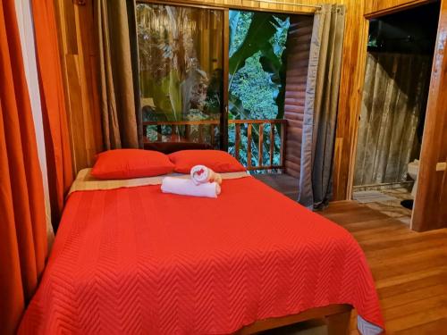a red bed with a towel on top of it at Arenal Rústic Lodge in Fortuna