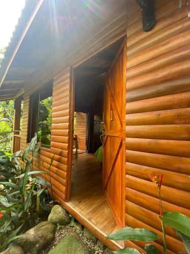 an open door of a wooden house with a porch at Arenal Rústic Lodge in Fortuna