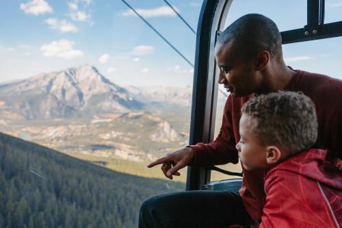 a man and a child on a train looking out a window at Banff Park Lodge in Banff