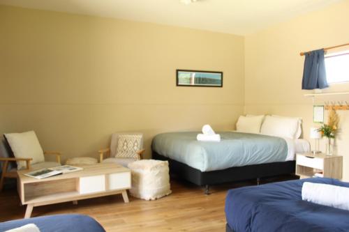 a hotel room with two beds and a chair at The Barn Cabins & Camp in Marahau