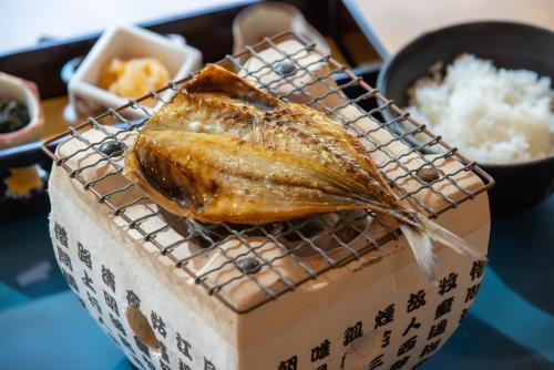 a fish on a wire rack next to a box of rice at Iki Stellacote Taiankaku in Iki