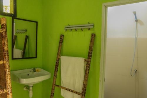 Baño verde con lavabo y espejo en Lendang Eco Lodge en Senggigi 