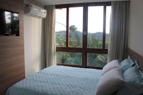 a bedroom with a bed and a large window at Flat em Vista Azul Hotel in Pedra Azul