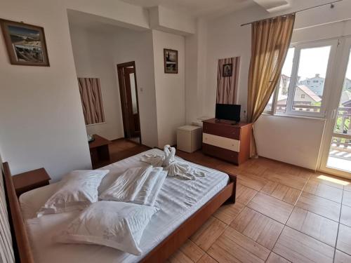 a bedroom with a bed with white sheets and a television at Vila Cristal Costinesti in Costinesti