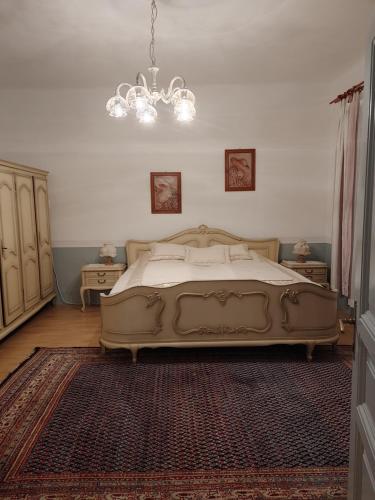 a bedroom with a large bed and a chandelier at Rokoko Apartman in Abádszalók