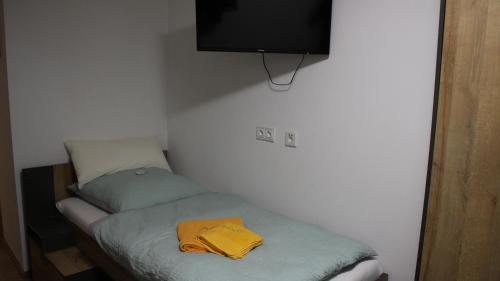 a small room with a bed with a yellow shirt on it at Pension und Gästehaus Paffrath in Großbrembach