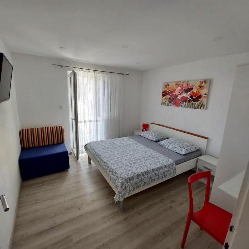 a small bedroom with a bed and a chair at Apartments Villa Antony in Drvenik