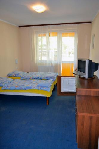 a bedroom with a bed and a dresser with a television at Pensjonat Resident in Krynica Morska