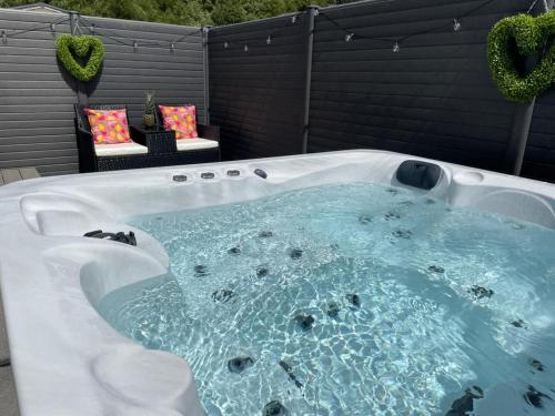 a jacuzzi tub in a backyard with two chairs at Hot Tub 9 The Fairways in Alnwick