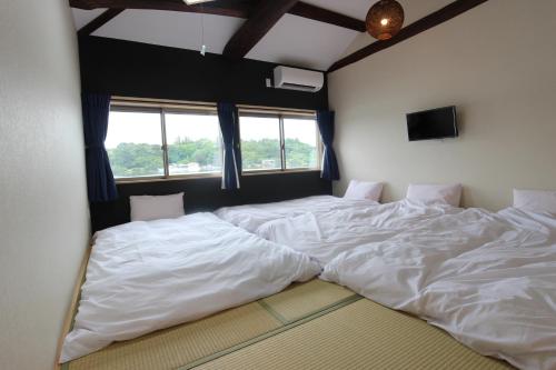 志摩市にあるYadokari Shimaの窓付きの客室で、白い大型ベッド2台が備わります。