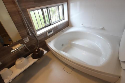 uma grande banheira branca numa casa de banho com uma janela em Yadokari Shima em Shima