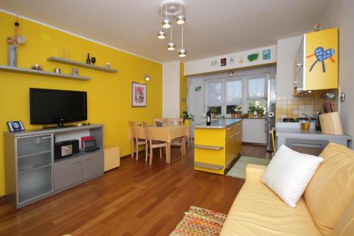 a living room with a couch and a kitchen with yellow walls at Apartment Bizjak in Pula