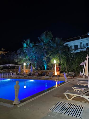 Nefis Hotel Ölüdeniz في أولدينيس: وجود مسبح في الليل مع الكراسي والنخيل