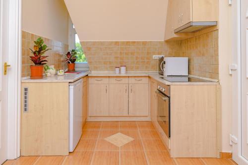 a small kitchen with wooden cabinets and appliances at ILLÉS Apartmanok II. in Hajdúszoboszló
