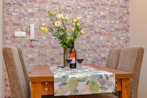 a table with a vase of flowers and two glasses of wine at ILLÉS Apartmanok II. in Hajdúszoboszló