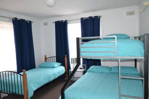 2 literas en una habitación con cortinas azules en Ocean Breeze, en Port Moonta