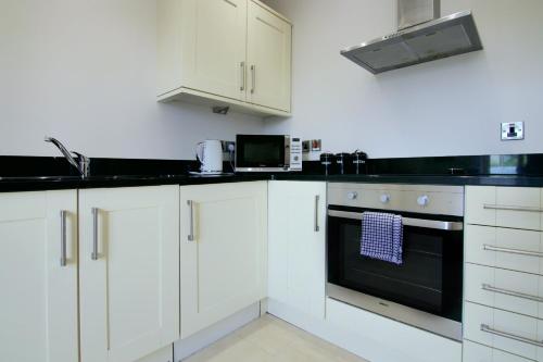 a kitchen with white cabinets and a black oven at Escape Ordinary at Castle Hume in Enniskillen