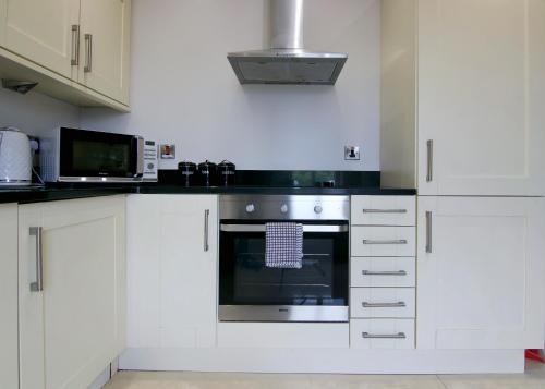 a kitchen with white cabinets and an oven at Escape Ordinary at Castle Hume in Enniskillen