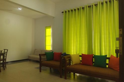 a living room with chairs and green curtains at Blue Water hikkaduwa in Hikkaduwa