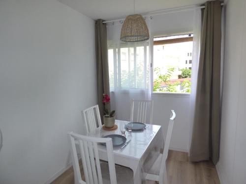 une table blanche et des chaises dans une pièce avec une fenêtre dans l'établissement Coquet Appartement T2, La Méditerranée, Narbonne Plage, à Narbonne-Plage