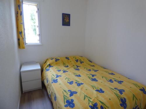 - une chambre dotée d'un lit jaune avec des fleurs bleues dans l'établissement Coquet Appartement T2, La Méditerranée, Narbonne Plage, à Narbonne-Plage