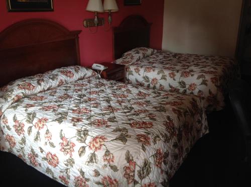 two beds in a hotel room with a floral bedspread at Executive Inn & Suites in Shepherd