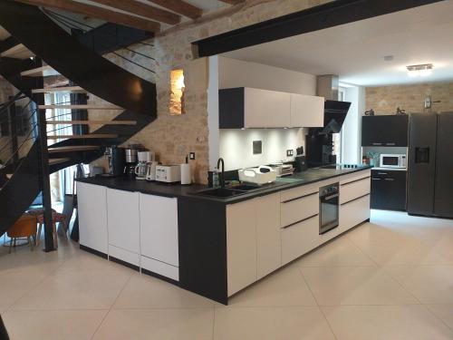 una cocina con armarios blancos y una escalera en Le Sourire du Troubadour - 8 chambres - Baignade à 300 m - Salle de jeux - Poêle à bois, en Daglan