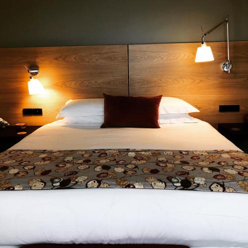 a bedroom with a large white bed with two lights at StoneTryst Spa Villas in Beechworth