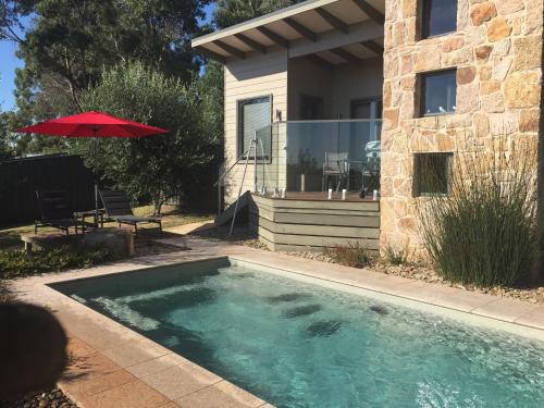 a swimming pool in front of a house with an umbrella at StoneTryst Spa Villas in Beechworth