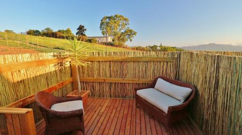 a wooden deck with two chairs and a fence at theLAB Robertson in Robertson