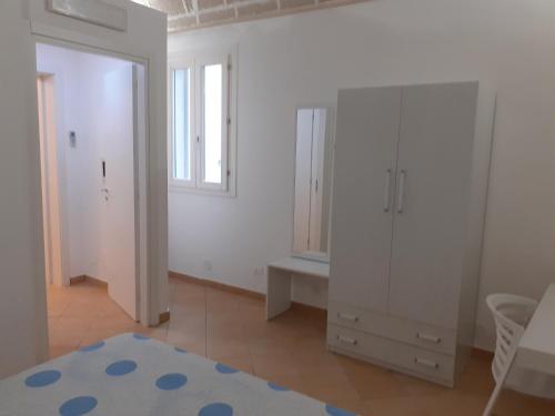 una camera da letto con armadi bianchi, finestra e specchio di La Dimora Del Vento a Marettimo