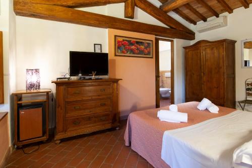 a bedroom with a bed and a dresser with a tv at Locanda Vesuna Hotel Countryhouse in Pienza