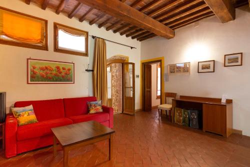 a living room with a red couch and a table at Locanda Vesuna Hotel Countryhouse in Pienza