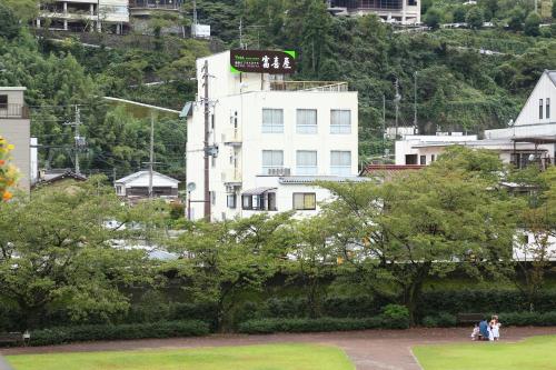 a white building with a sign on it in a city at Fukiya in Gero