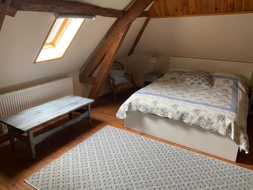 a bedroom with a bed and a bench in a attic at Maison 6 personnes La Tourelle in Saulchoy