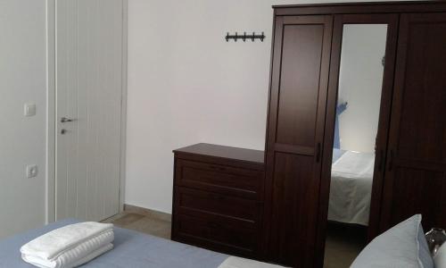 a bedroom with a wooden dresser and a mirror at Stilvi Milos in Plaka Milou