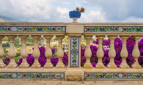 a fence with purple flowers and a vase on top at Nnakkara Guest House in Santo Stefano di Camastra