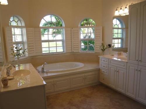 a bathroom with a tub and two sinks and windows at Villa Cape Florida in Cape Coral