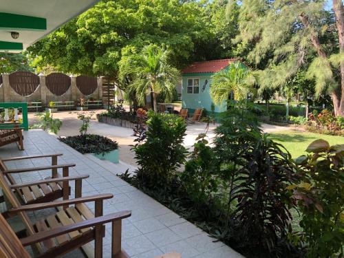 a patio with benches and trees and a house at Belize Budget Suites in San Pedro