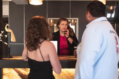 a woman talking to a man in front of a mirror at Hôtel 1770 & Spa in Le Pontet