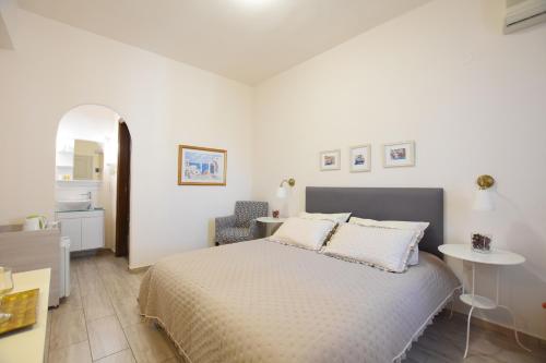 a white bedroom with a bed and a chair at Rodakas Hotel in Akrotiri