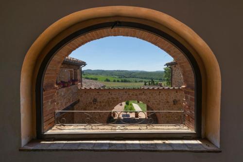 an arched window in a brick wall with a view at Locanda Vesuna Hotel Countryhouse in Pienza