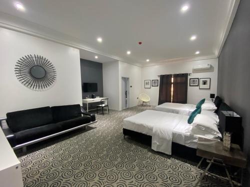 a bedroom with a bed and a couch and a desk at MUSE Boutique Hotel in Enugu