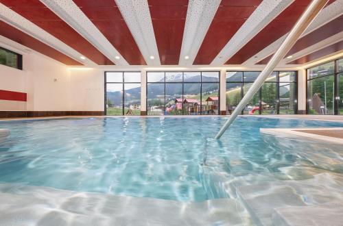 a large swimming pool in a building with windows at Hotel Sunny Sölden in Sölden