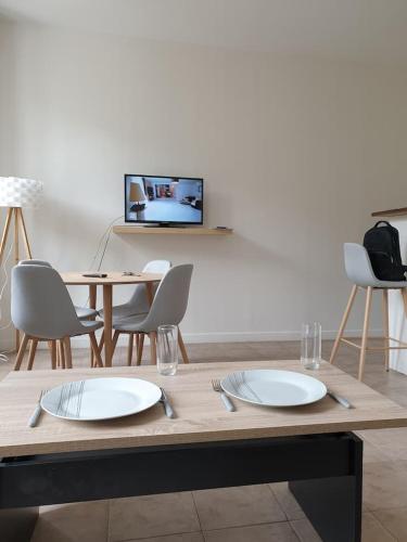 Studios des Remparts - Avallon في أفالون: طاولة بها طبقين وكراسي وتلفزيون